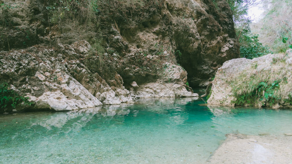 How to Visit Cascada El Aguacate: San Luis Potosi, Mexico 10 A tranquil turquoise pool surrounded by rocky cliffs and greenery at Cascada El Aguacate in Huasteca Potosina. The crystal-clear water reflects the natural limestone formations and lush vegetation.