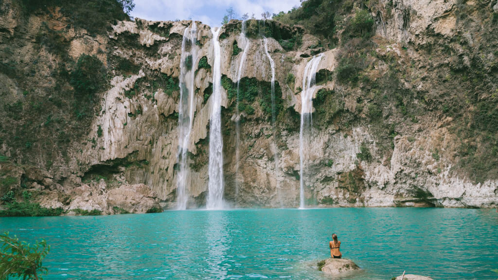 Sally sitting on a rock in front of a waterfall in Huasteca Potosina