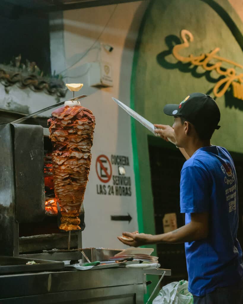 A man slicing meat of a spit at a taco stand in Puerto Vallarta