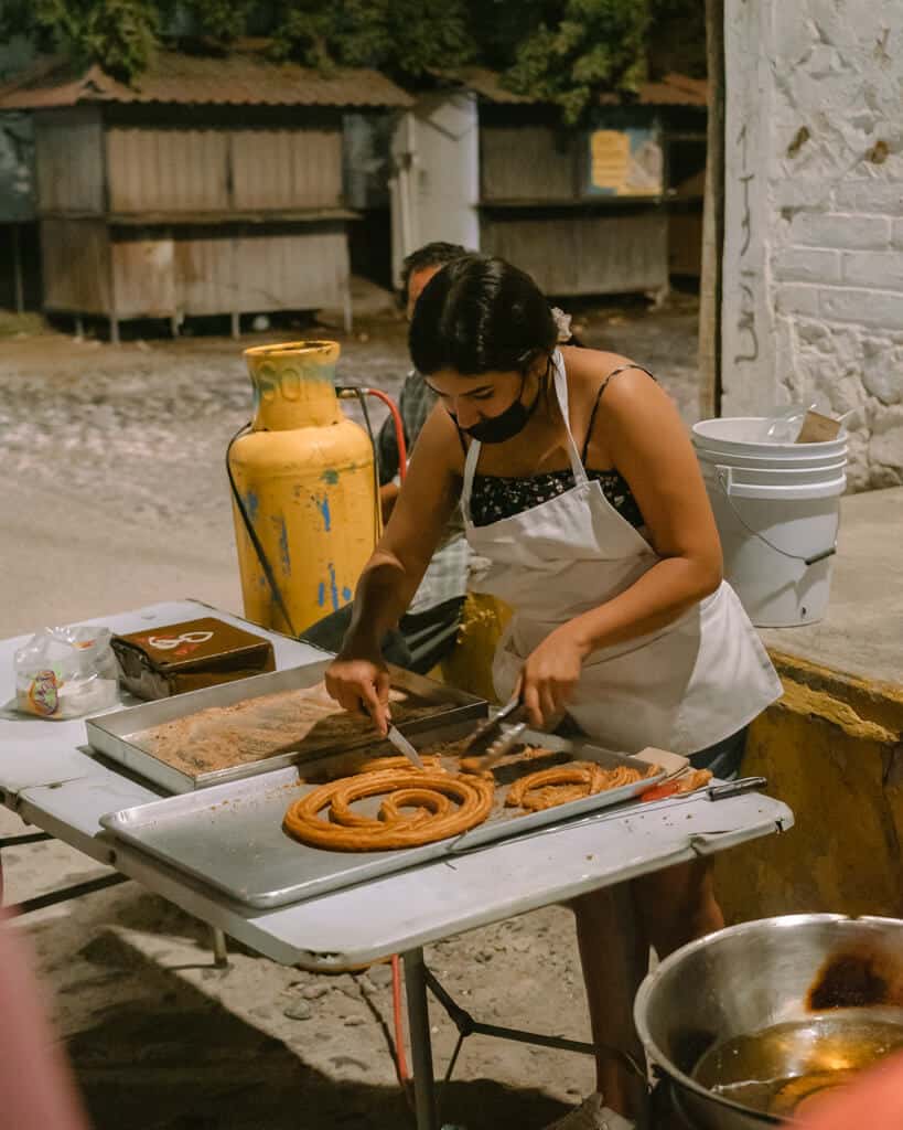 A lady chopping churros on a table at a street stall in Puerto Vallarta