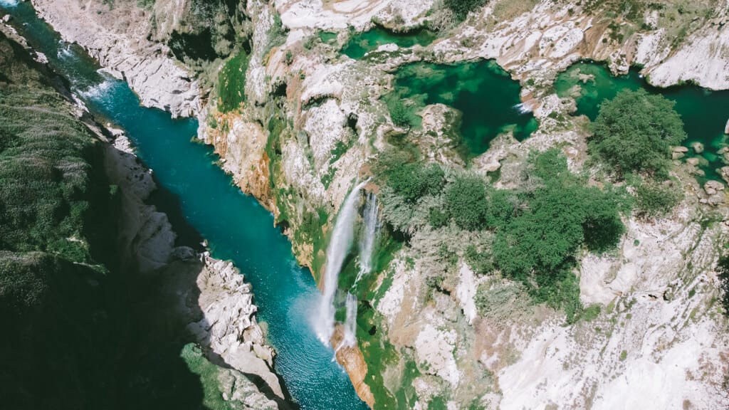 A drone shot of Cascada de Tamul spilling over a canyon into a blue river, one of the best Huasteca Potosina waterfalls