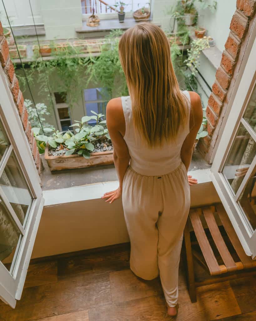El Patio 77: Sustainable Bed and Breakfast Mexico City 8 Sally leaning over an open window sill looking over an internal courtyard with greenery and plants on the window sill