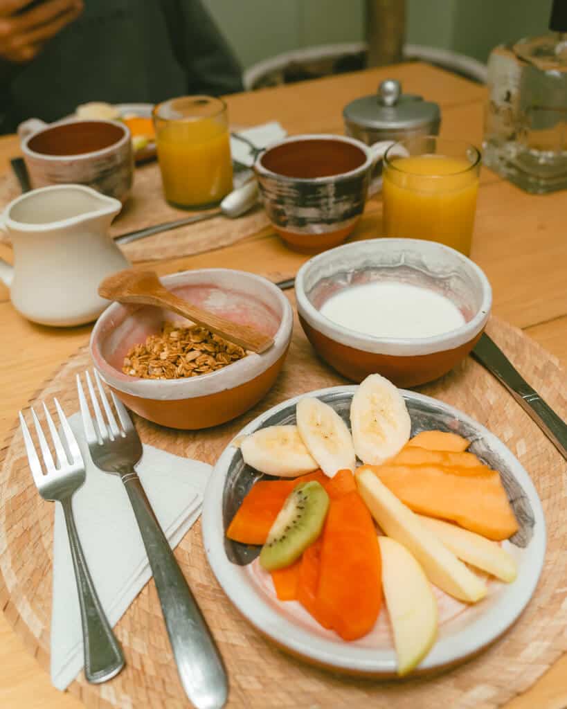 El Patio 77: Sustainable Bed and Breakfast Mexico City 20 A table set for breakfast with a plate of fruit, a bowl of yoghurt, a bowl of muesli and cups of coffee and juice