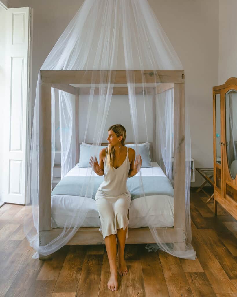 El Patio 77: Sustainable Bed and Breakfast Mexico City 11 Sally sitting on the edge of a bed with a fancy mosquito net hanging over the bed, she is parting it with her hands
