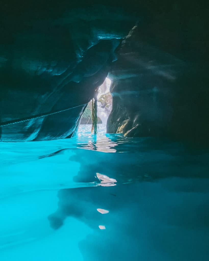 How to Visit Puente de Dios: Tamasopo, Huasteca Potosina 9 Inside the cave at Puente de Dios in Huasteca Potosina, sunlight streams through the opening onto the glowing turquoise water. The smooth rock walls and reflections create a mystical, serene atmosphere.