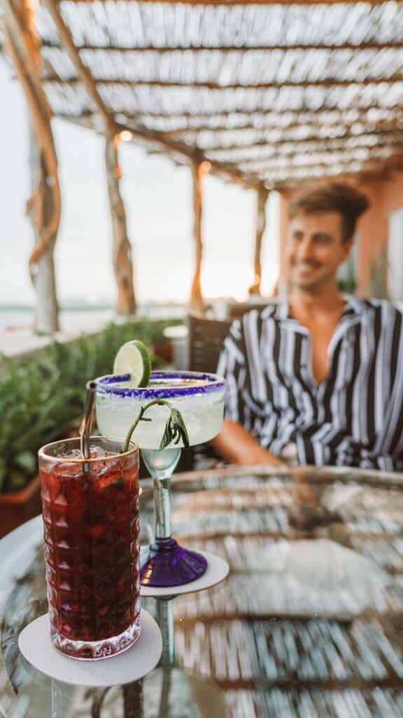 Casa Tortugas Boutique Hotel - Sustainable Accommodation in Cancun 21 Brayden out of focus behind two colourful cocktails from the rooftop bar at Casa Tortugas Boutique Hotel