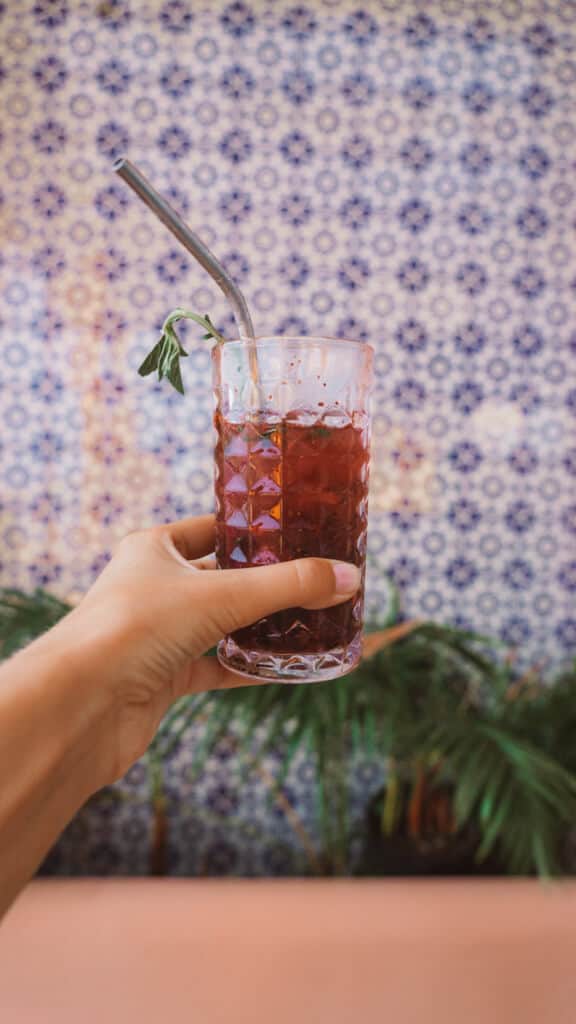 Casa Tortugas Boutique Hotel - Sustainable Accommodation in Cancun 27 A red cocktail in a glass with a metal straw against a patterned tile wall