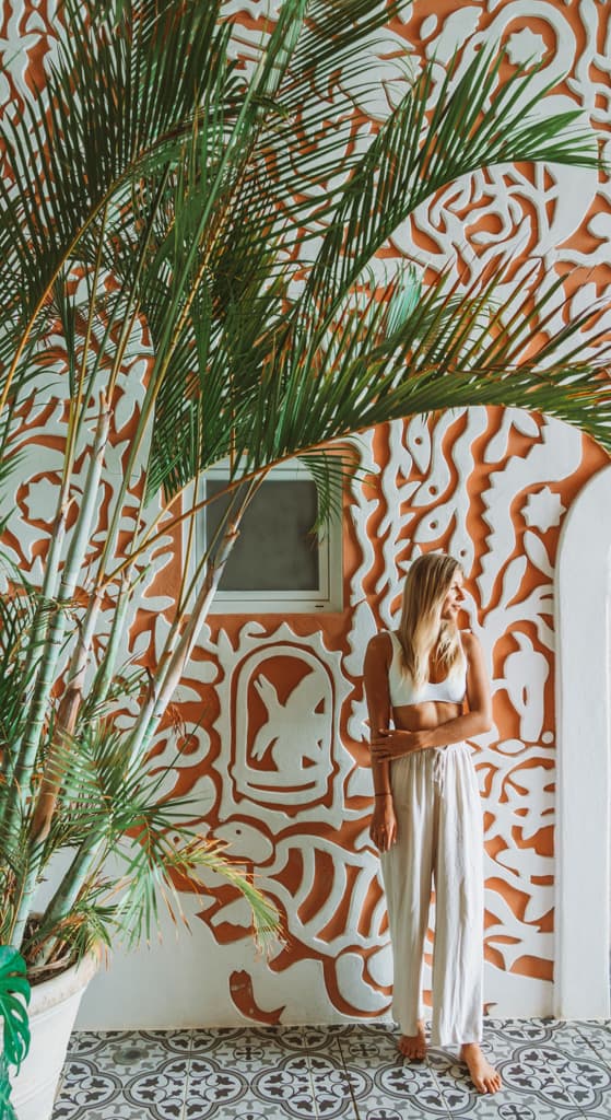 Casa Tortugas Boutique Hotel - Sustainable Accommodation in Cancun 14 Sally standing in front of an orange wall with abstract shapes