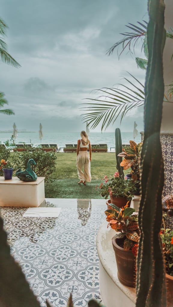 Casa Tortugas Boutique Hotel - Sustainable Accommodation in Cancun 17 Sally walking across a lawn towards a water view with grey skies behind her