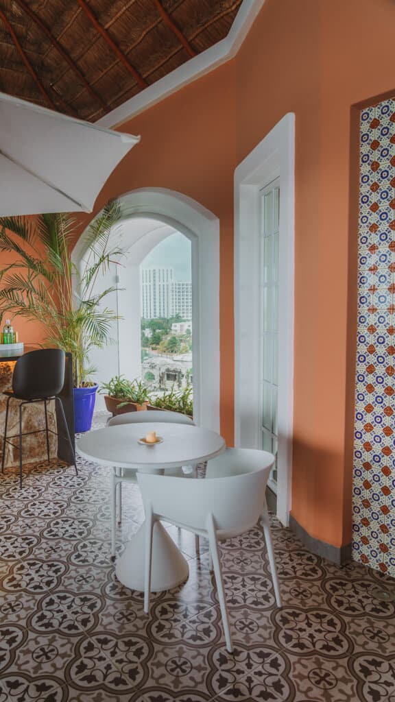 Casa Tortugas Boutique Hotel - Sustainable Accommodation in Cancun 19 A white chair and table against patterned floor and wall tables at the rooftop bar at Casa Tortugas Boutique Hotel