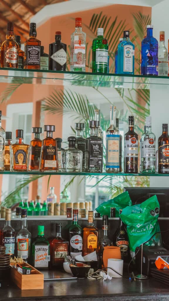 Casa Tortugas Boutique Hotel - Sustainable Accommodation in Cancun 24 Shelves of liquor bottles mounted on a mirrored wall at Casa Tortugas Boutique Hotel