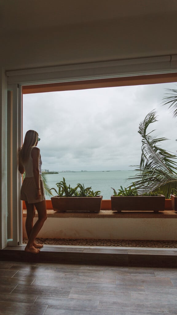 Casa Tortugas Boutique Hotel - Sustainable Accommodation in Cancun 6 Sally standing by an open sliding glass door on a balcony overlooking the lagoon at Casa Tortugas Boutique Hotel
