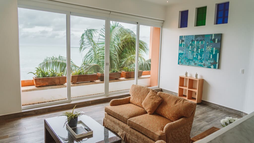 Casa Tortugas Boutique Hotel - Sustainable Accommodation in Cancun 8 A large loungeroom with orange couches against large floor to ceiling windows