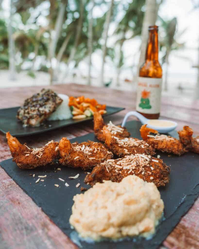 Glamping at Hotel Cielo y Selva in the Sian Ka'an Biosphere Reserve 31 Coconut crusted shrimp on a plate with mashed vegetables in front of it and a beer bottle in the background