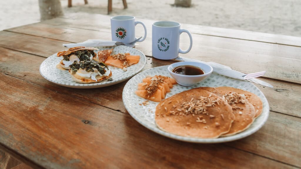 Glamping at Hotel Cielo y Selva in the Sian Ka'an Biosphere Reserve 33 Coconut hotcakes and eggs benedict on an outside table with two coffee cups in the background