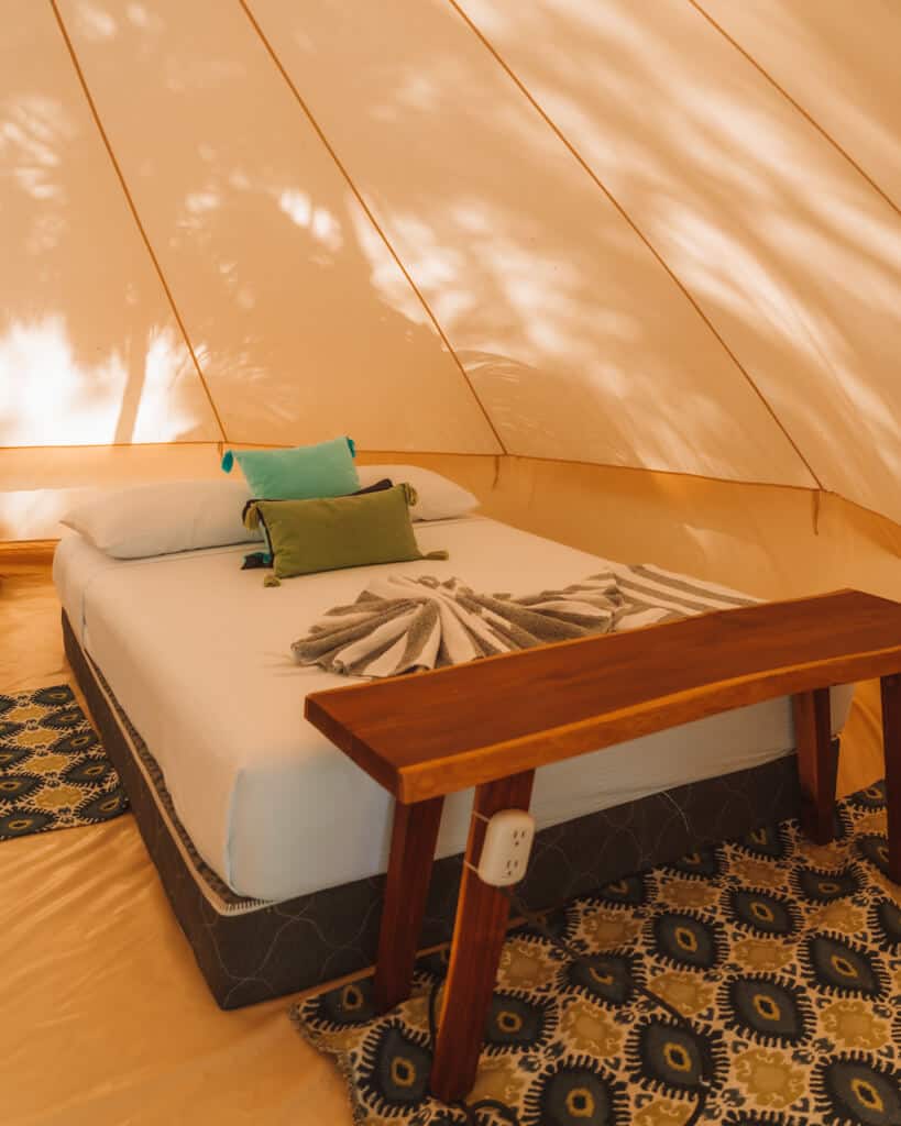 Glamping at Hotel Cielo y Selva in the Sian Ka'an Biosphere Reserve 14 A double bed inside a glamping tent with a wooden bench at the foot at Hotel Cielo y Selva