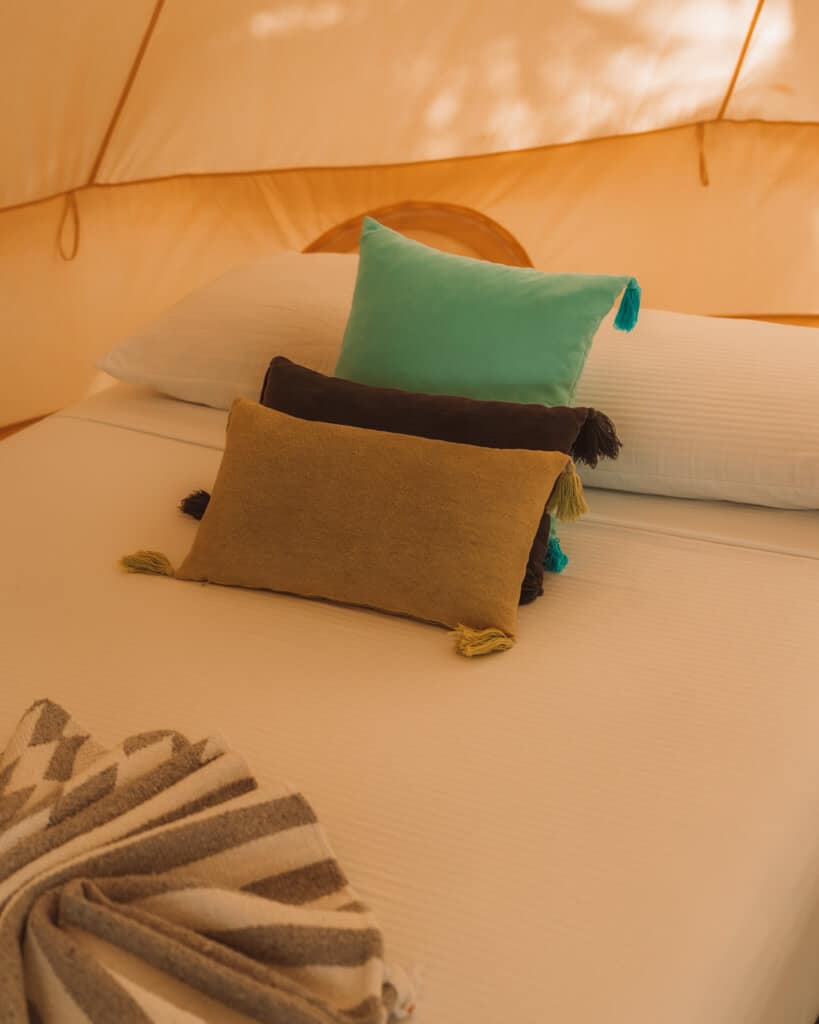 Glamping at Hotel Cielo y Selva in the Sian Ka'an Biosphere Reserve 15 Three coloured cushions stacked on a bed inside a glamping tent