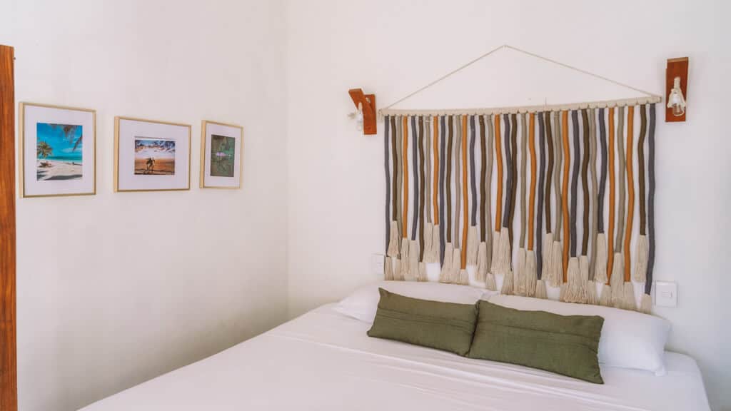 Glamping at Hotel Cielo y Selva in the Sian Ka'an Biosphere Reserve 20 A double bed in a hotel room with green cushions on the bed and a woven wall hanging above the bed
