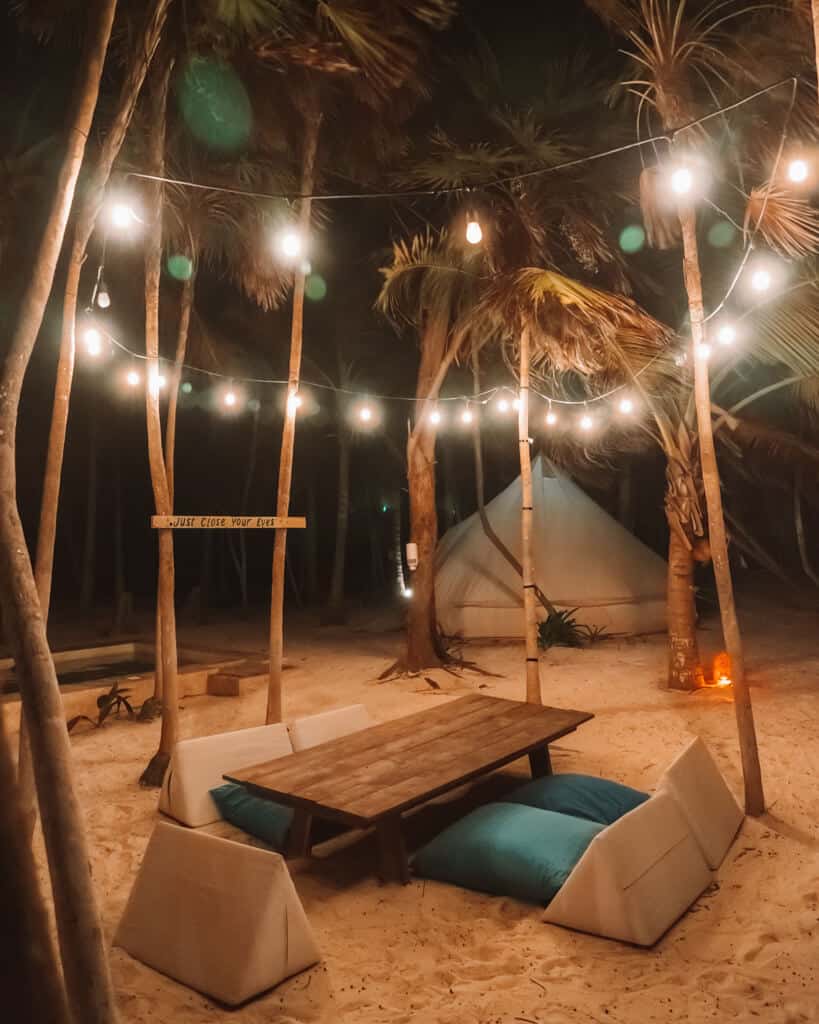 Glamping at Hotel Cielo y Selva in the Sian Ka'an Biosphere Reserve 27 Glass string lights in palm trees above a table and floor cushions at Hotel Cielo y Selva