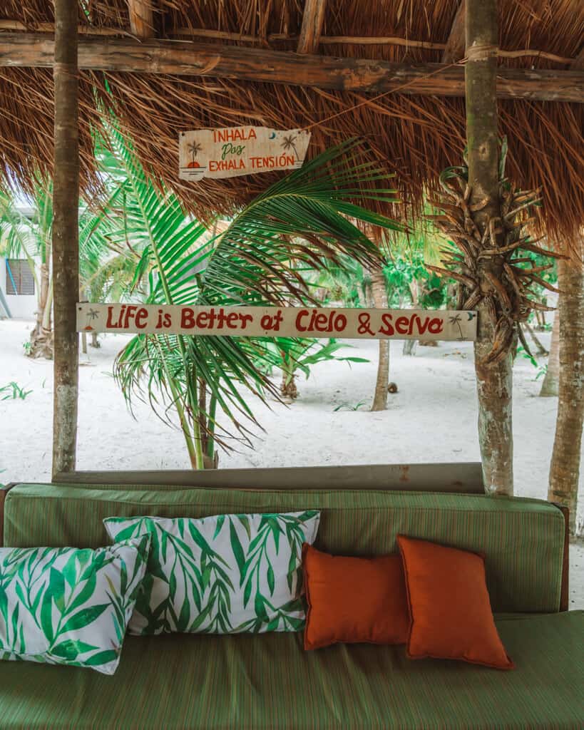 Glamping at Hotel Cielo y Selva in the Sian Ka'an Biosphere Reserve 30 A lounge with four cushions, with a wooden sign above saying 'life is better at Cielo & Selva'