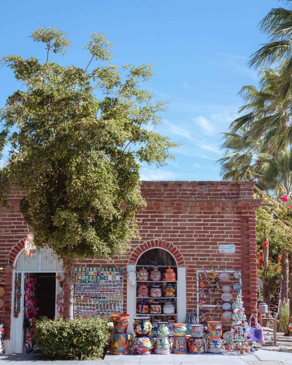 Exploring all the historic buildings and souvenir shops is one of the best things to do in Todos Santos, with a red brick building selling pottery and souvenirs spilling out on the sidewalk