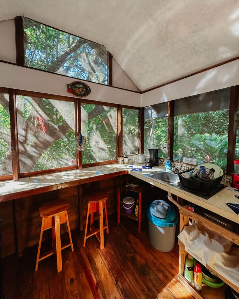 Where to Stay in San Ignacio Belize: Town or Jungle Lodge? 8 An open-air bug screened kitchen surrounded by greenery at Hummingbird Rest, a hotel in San Ignacio Belize.