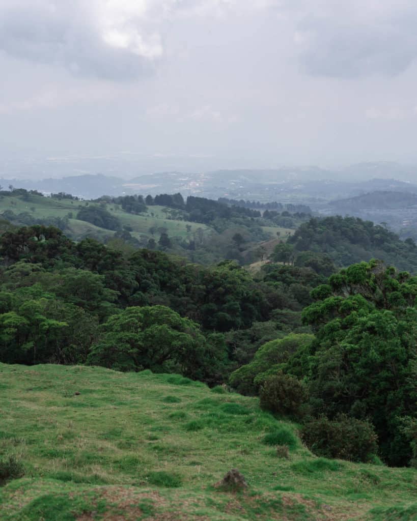Bajos del Toro Travel Guide: Costa Rica's Waterfall Wonderland 7 A landscape scene of green rolling hills with trees and paddocks in Bajos del Toro