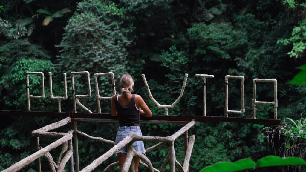 Costa Rica Travel Guide: Planning The Perfect Pura Vida Trip 8 Sally standing in front of big letters handmade from pipe saying pura vida with rainforest in the background