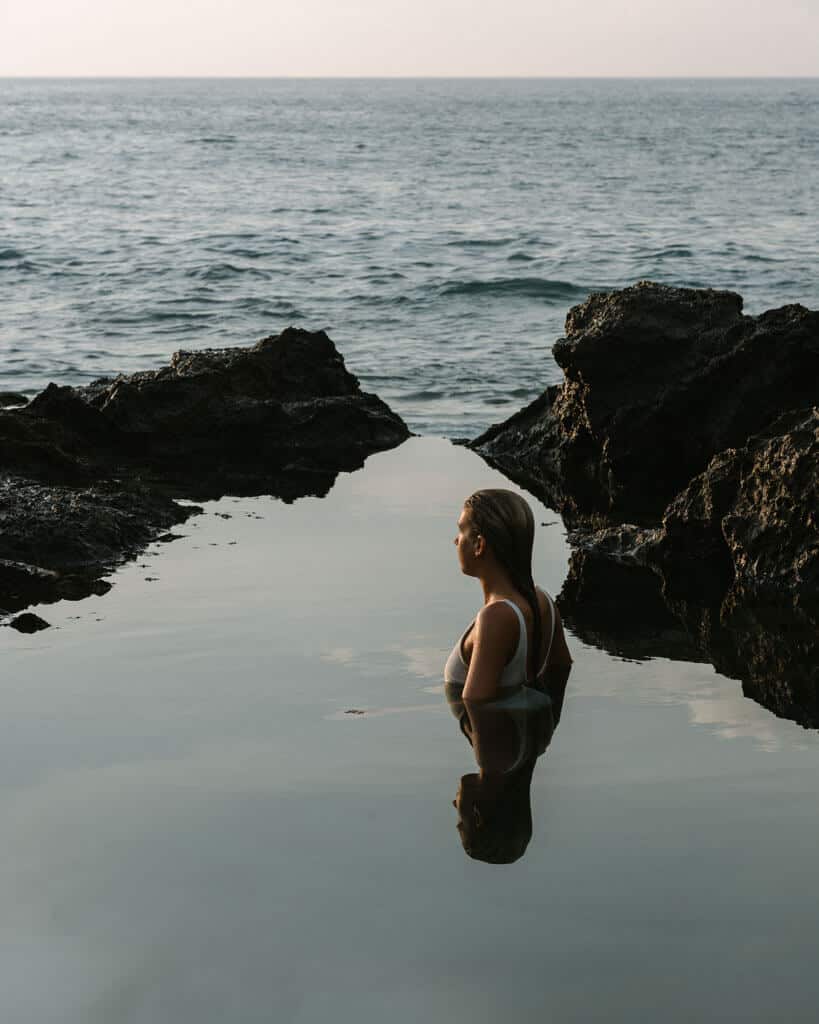 Sally in serene contemplation, seated in a natural rock pool by the sea in Montezuma