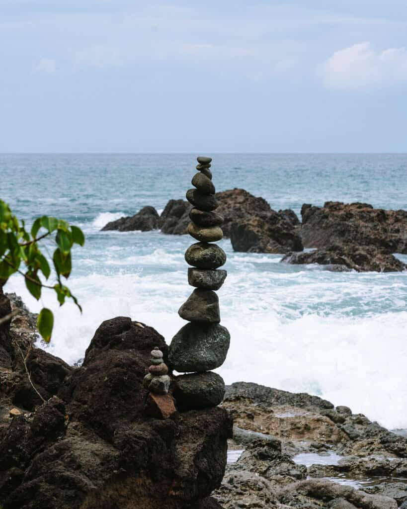 15 Best Things to Do in Montezuma Costa Rica 20 A 'cairn' or tall stack of rocks on the beach in Montezuma, with the ocean crashing in the background