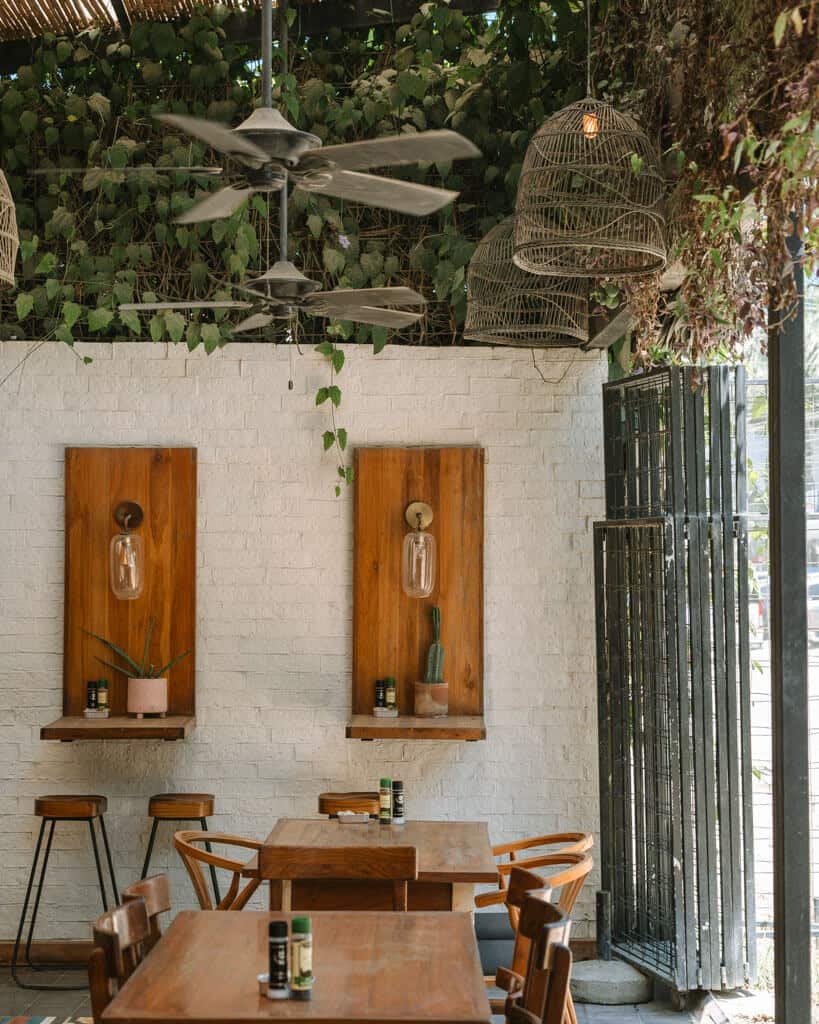 15 Best Things to Do in Montezuma Costa Rica 27 A funky cafe in Santa Teresa, with greenery growing on the roof, wooden tables and chairs, and large light fittings hanging