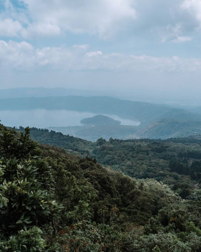 Is El Salvador Safe to Travel? Our Experience & Safety Tips 8 A towering view over Lago de Coatepeque framed by lush greenery, showing the large volcanic crater lake surrounded by mountainous terrain under a cloud-filled sky.