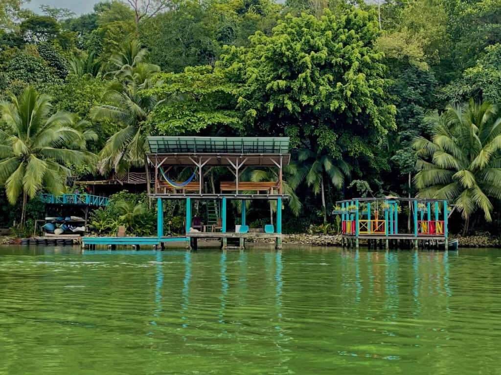 Complete Guide to Rio Dulce Guatemala 13 Colourful waterfront cabins and hammocks surrounded by tropical jungle at Palmeras del RĂo in RĂo Dulce, Guatemala.