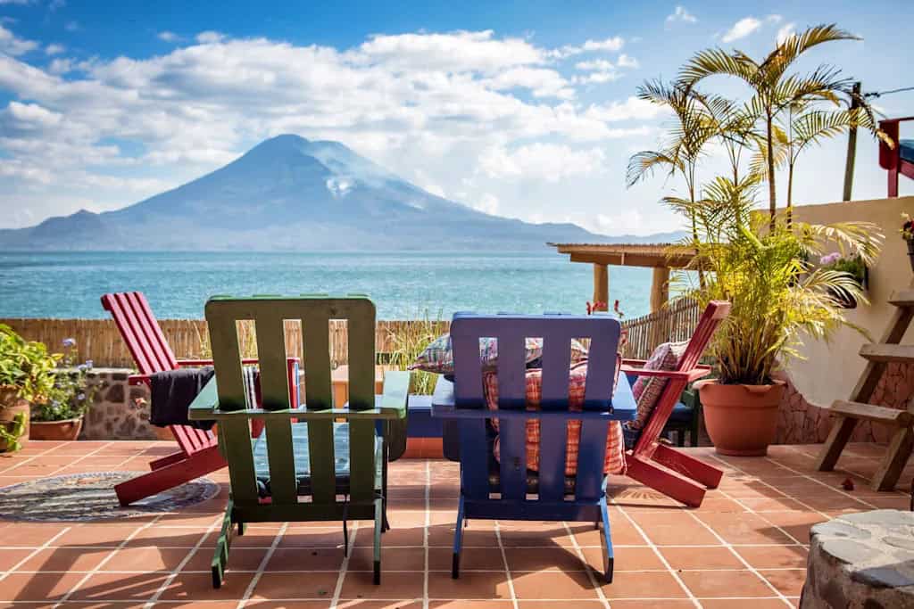 Lake Atitlan Travel Guide: Everything You Need to Know 11 Colourful outdoor seating area overlooking Lake Atitlán and volcano views at Iguana Perdida hostel in Santa Cruz La Laguna, Guatemala.