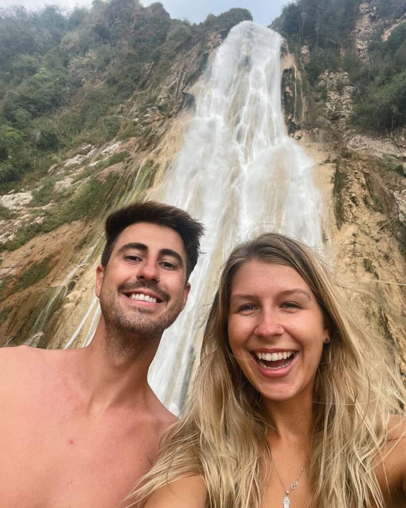 Cascadas El Chiflon: Without a Tour + Overnight Stay 21 A selfie of Sally and Brayden in front of Cascada Velo de Novia. Both are smiling widely, with the waterfall cascading in the background and creating a refreshing backdrop, with the effects of the wind seen in their hair.