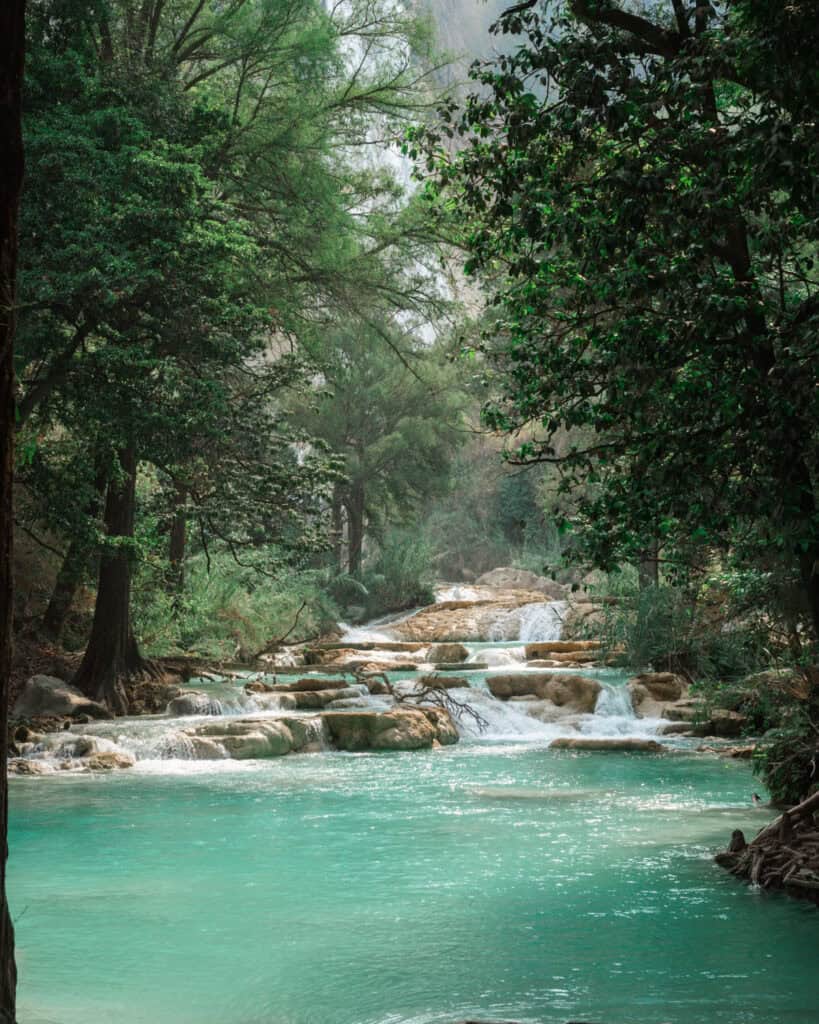 Cascadas El Chiflon: Without a Tour + Overnight Stay 2 A serene view of turquoise water flowing through small waterfalls surrounded by lush, green trees, creating a peaceful natural setting at Cascadas El Chiflón.