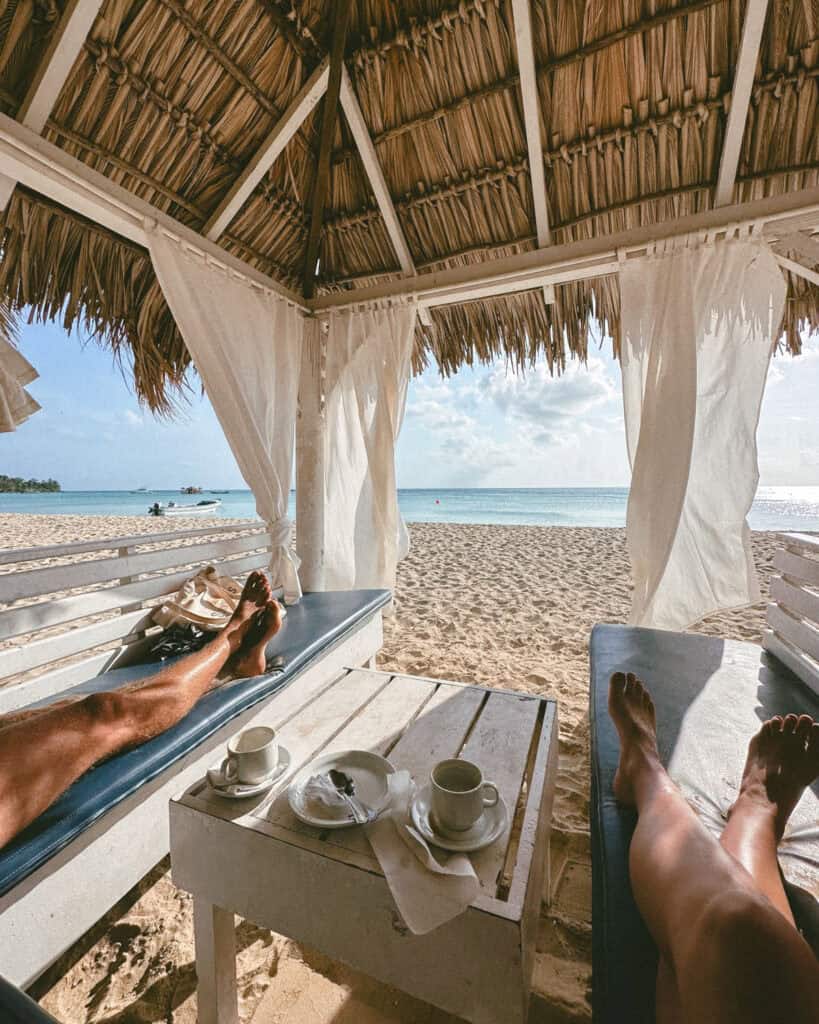 Big Corn Island, Nicaragua: The Underrated Corn Island 28 Inside a cozy cabana at Arenas Beach Club, showing two lounge chairs with cups of coffee on a small table, overlooking the beach and ocean.