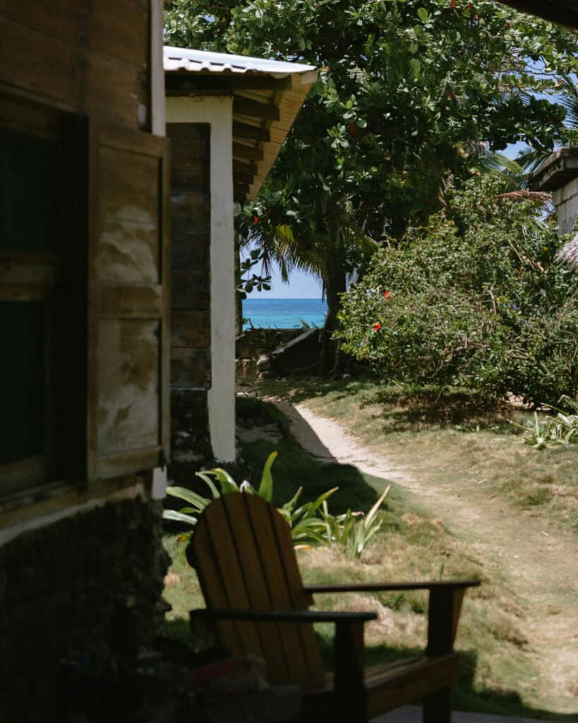 Corn Islands Nicaragua: Paradise on Big & Little Corn 27 A scenic path leading from a rustic beachfront cabin, bordered by hibiscus bushes and tropical greenery, with the ocean peeking through in the background.