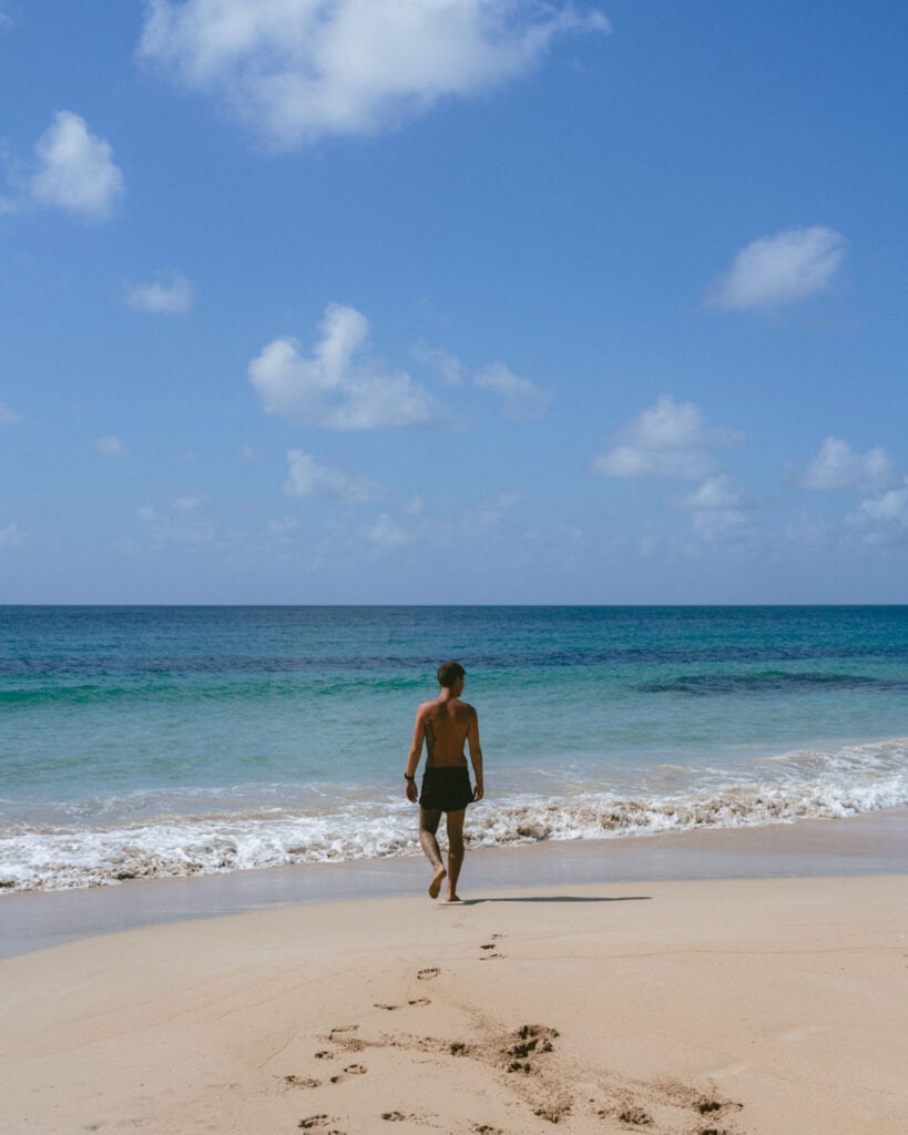 Nicaragua Travel Guide: Land of Lakes and Volcanoes 5 Brayden walking along the shoreline at Long Bay Beach, leaving footprints in the sand as waves gently roll in.