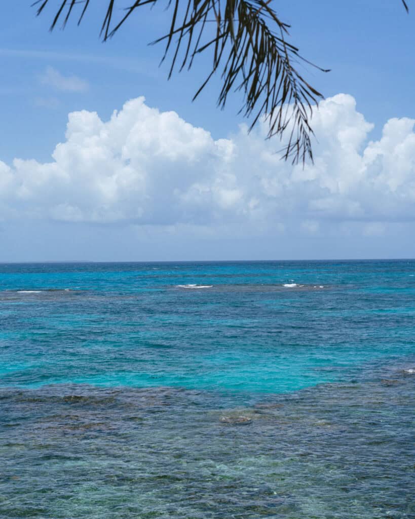 Big Corn Island, Nicaragua: The Underrated Corn Island 18 A vibrant view of a reef on the north side of Big Corn Island, showing crystal-clear turquoise waters under a blue sky with scattered clouds.
