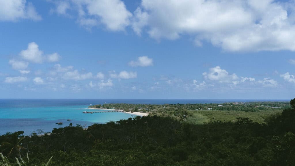 Big Corn Island, Nicaragua: The Underrated Corn Island 40 A view from Quinn Hill Mirador capturing the vast ocean, a stretch of beach, and surrounding greenery under a bright blue sky in Big Corn Island, Nicaragua.