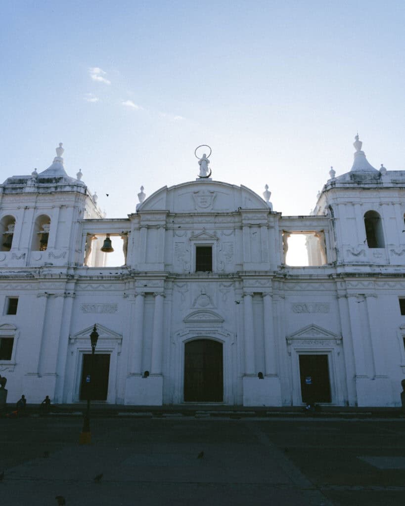 18 Best Things to Do in Leon, Nicaragua 2 A frontal view of the León Cathedral’s grand facade, with ornate white columns and statues silhouetted against a clear sky.