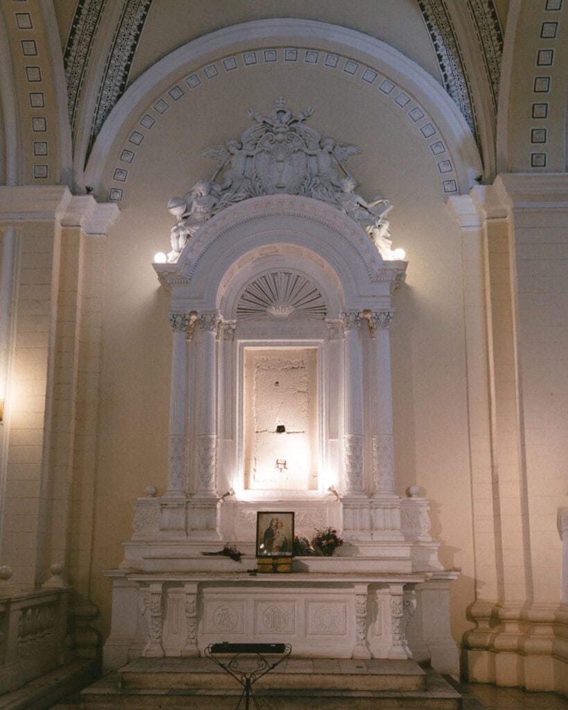 18 Best Things to Do in Leon, Nicaragua 9 A beautifully detailed altar inside León Cathedral, featuring ornate columns, angel sculptures, and a framed image of the Virgin Mary, surrounded by soft lighting.