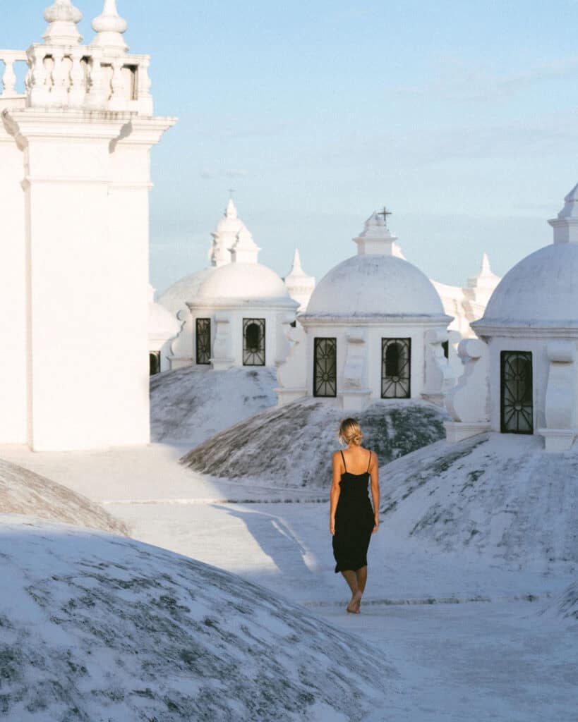 18 Best Things to Do in Leon, Nicaragua 12 Sally walking further across the León Cathedral rooftop, her figure contrasting with the bright white architecture and the deep blue sky.
