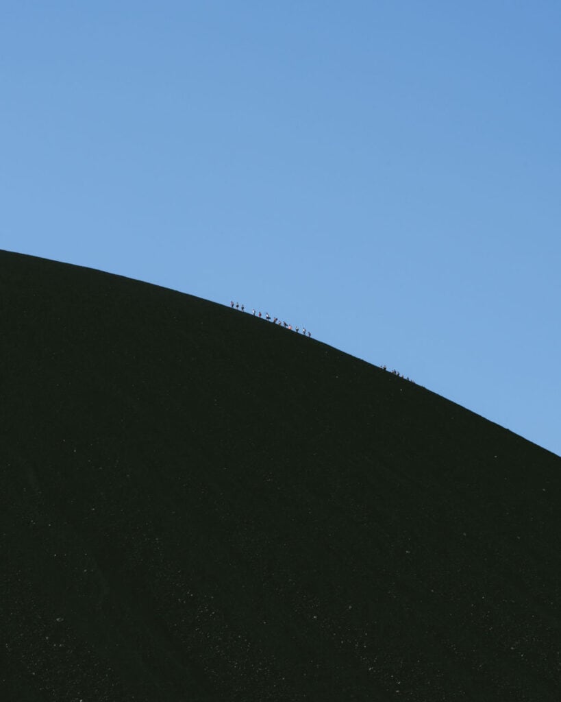 Epic Volcano Boarding in Nicaragua at Cerro Negro Volcano 14 A group of climbers silhouetted against the sky as they ascend the steep, black slopes of Cerro Negro Volcano.