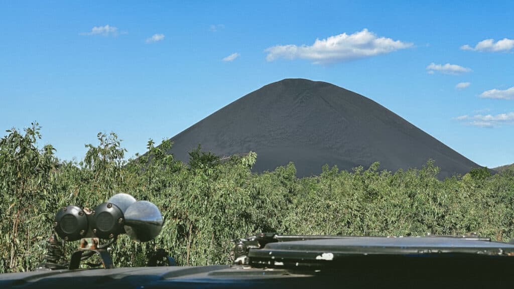 Epic Volcano Boarding in Nicaragua at Cerro Negro Volcano 13 A panoramic view of Cerro Negro Volcano’s stark black slopes contrasted with the lush green plains and distant mountains.