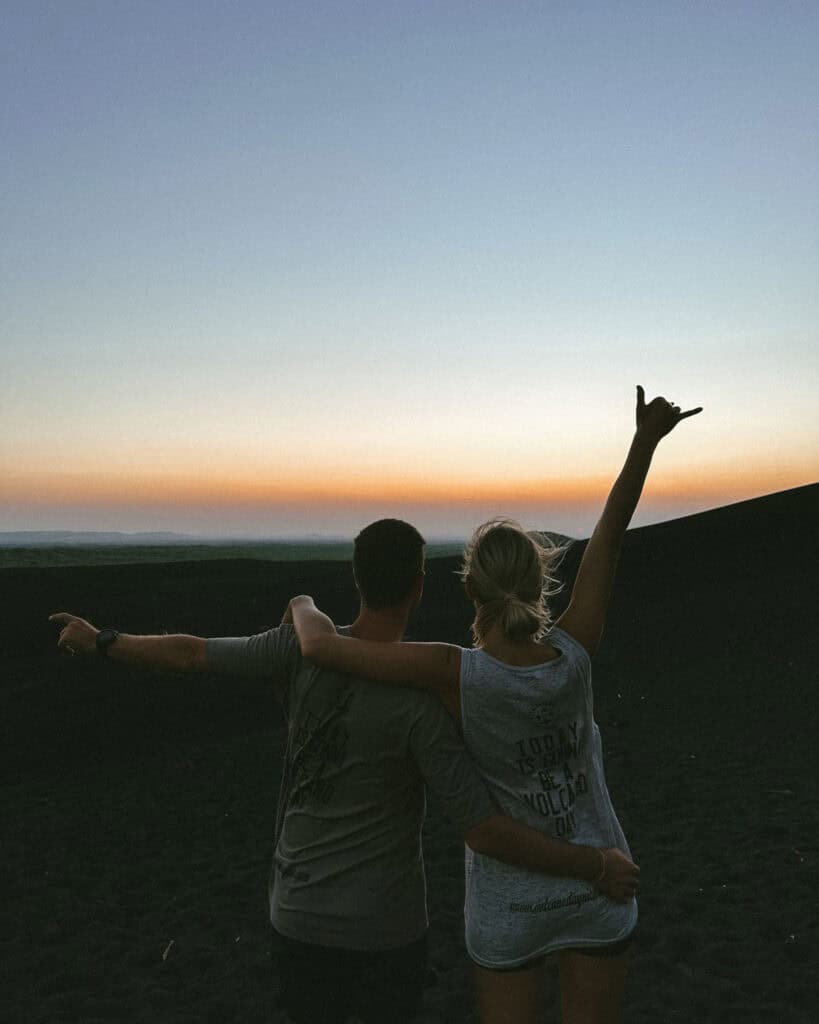 Epic Volcano Boarding in Nicaragua at Cerro Negro Volcano 24 Brayden and Sally wearing Volcano Day tops against a sunset sky at Cerro Negro Volcano