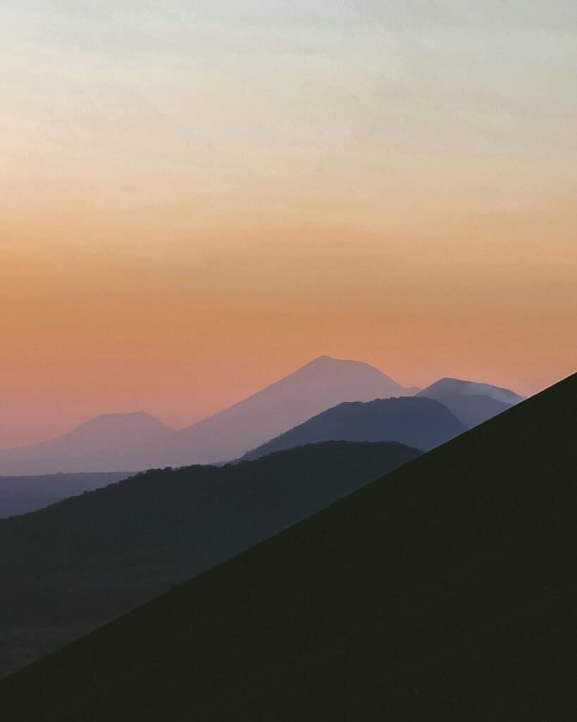 Epic Volcano Boarding in Nicaragua at Cerro Negro Volcano 23 A vibrant sunset with hues of orange and pink illuminating the distant volcanic peaks near Cerro Negro in Leon, Nicaragua.