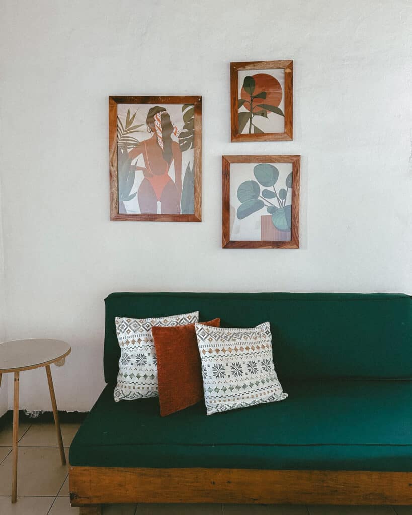 Leon, Nicaragua Travel Guide: The City of Revolution 16 A comfortable lounge area in one of the apartments at Coco Calala, Leon, with a green sofa adorned with patterned cushions, wooden frames with modern art on the wall, and a small side table.