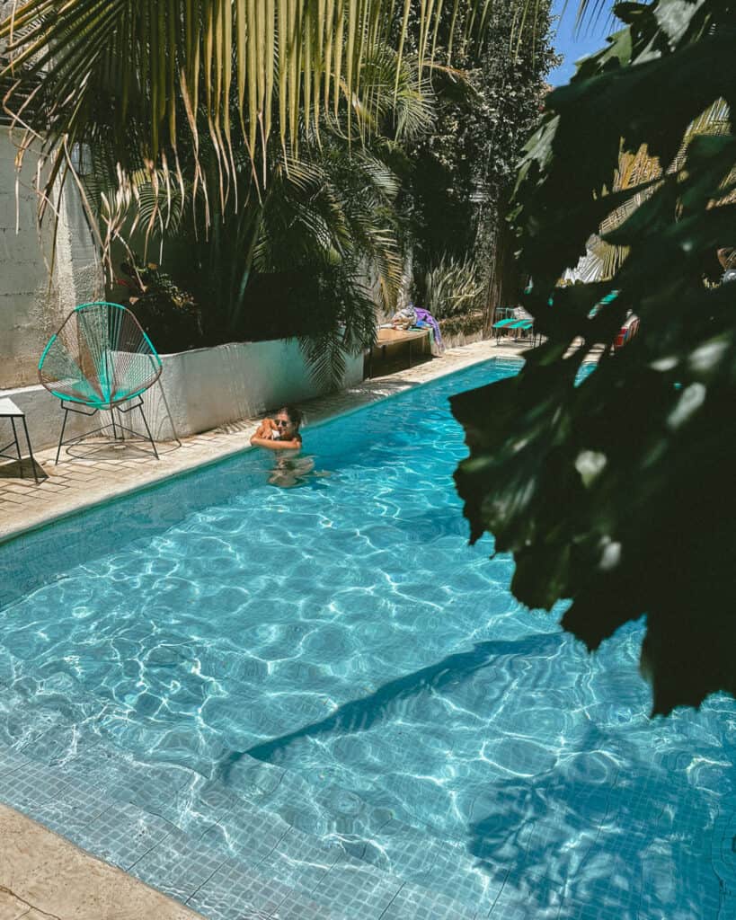 18 Best Things to Do in Leon, Nicaragua 33 A vibrant scene of Sally enjoying a swim in the refreshing pool at Coco Calala, Leon, surrounded by lush greenery and cozy poolside seating.